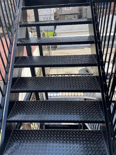 A close up of a set of black metal stairs leading up to a building.