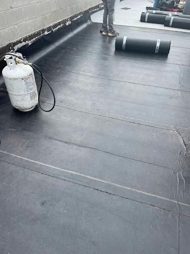 A propane cylinder is sitting on top of a black roof.