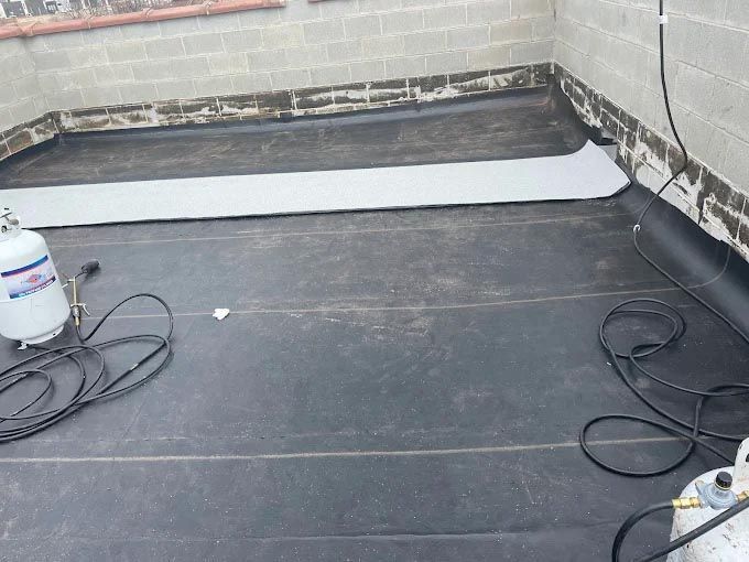 A propane tank is sitting on the floor next to a hose.