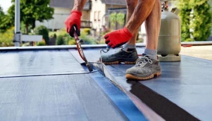 A man wearing red gloves is working on a roof.