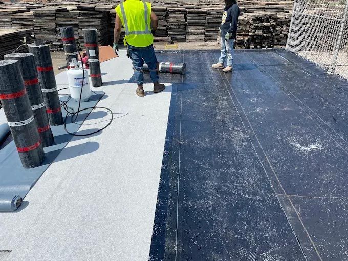 A man in a yellow vest is standing on a roof.