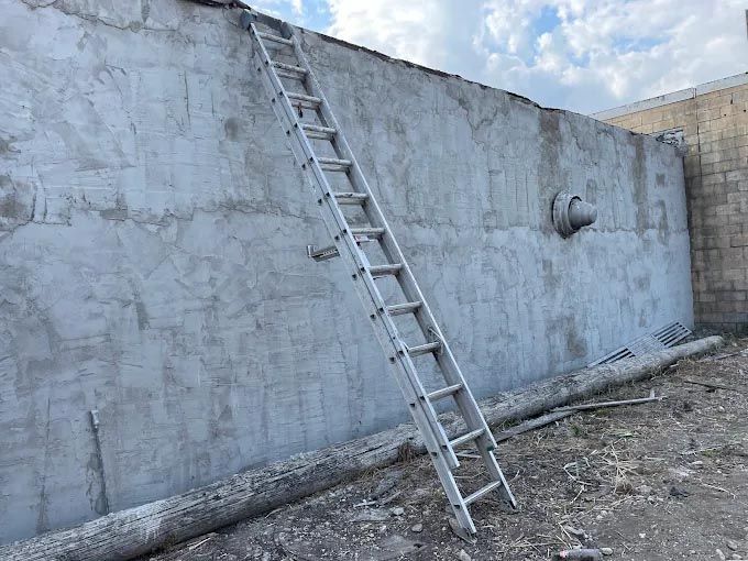 A ladder is leaning against a concrete wall.