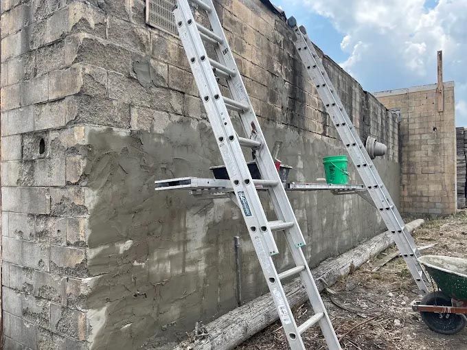 A ladder is leaning against a brick wall next to a wheelbarrow.