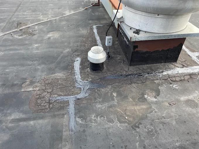 A roof with a fan on top of it and a hole in it.