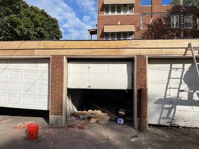 A garage with the door open and a red bucket in front of it