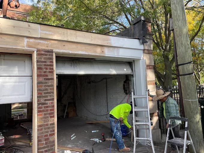 A man is standing on a ladder in front of a garage door.