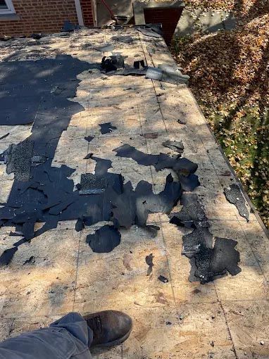 A person is standing on a roof that has been damaged by a fire.