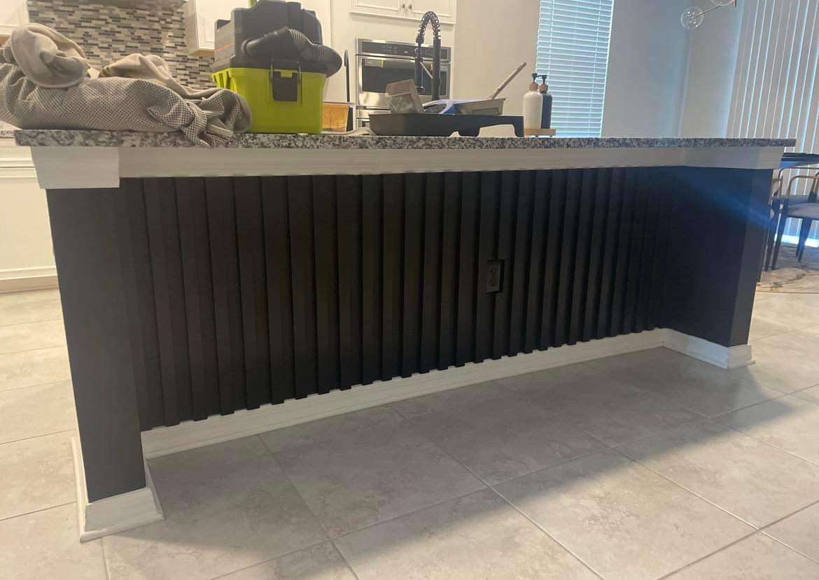 A cat is laying on top of a kitchen island.