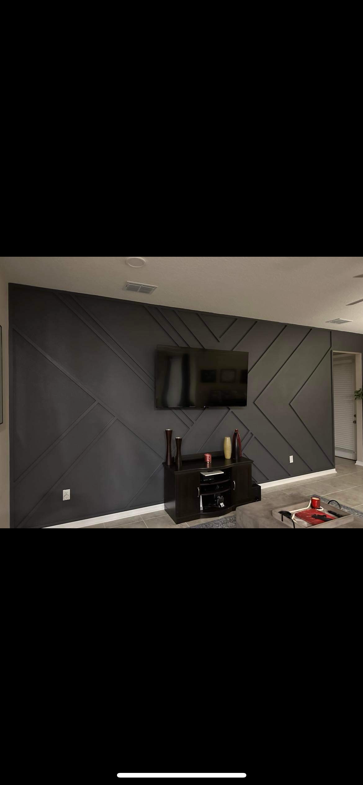 A living room with a gray wall and a flat screen tv.