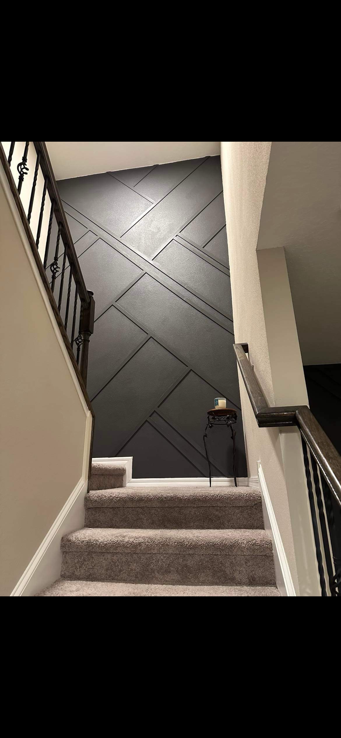 A picture of a staircase with a black wall and a railing.