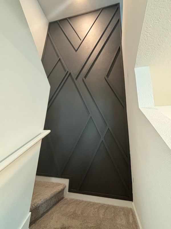 A staircase with a black wall and a white railing