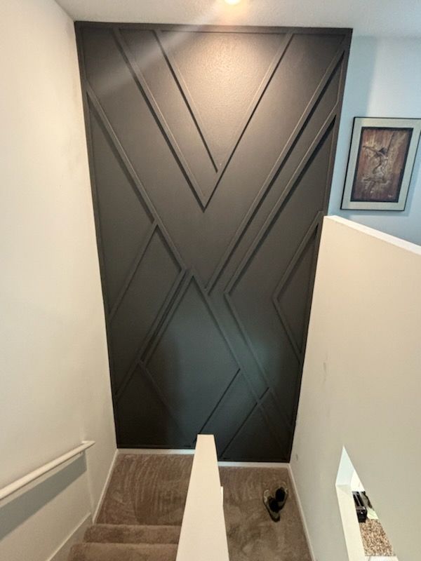 A staircase with a black wall and a picture on the wall.