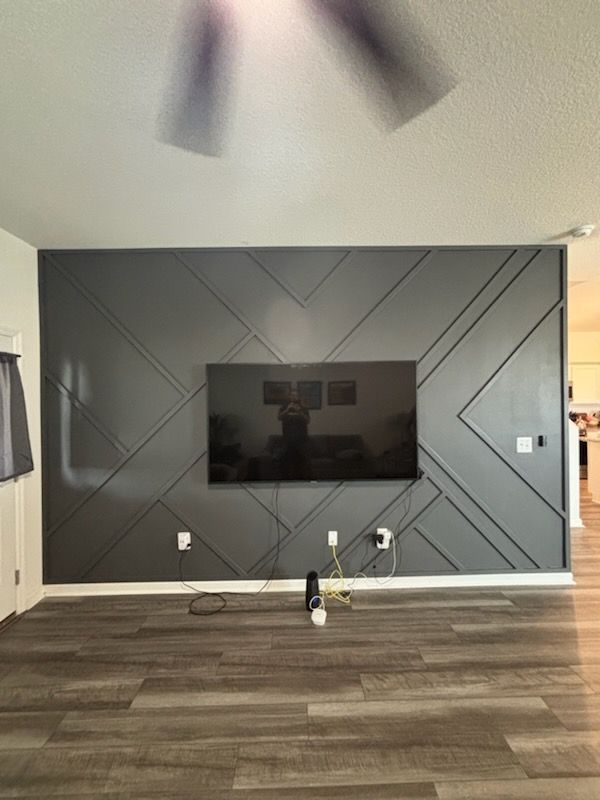 A living room with a ceiling fan and a flat screen tv on the wall.