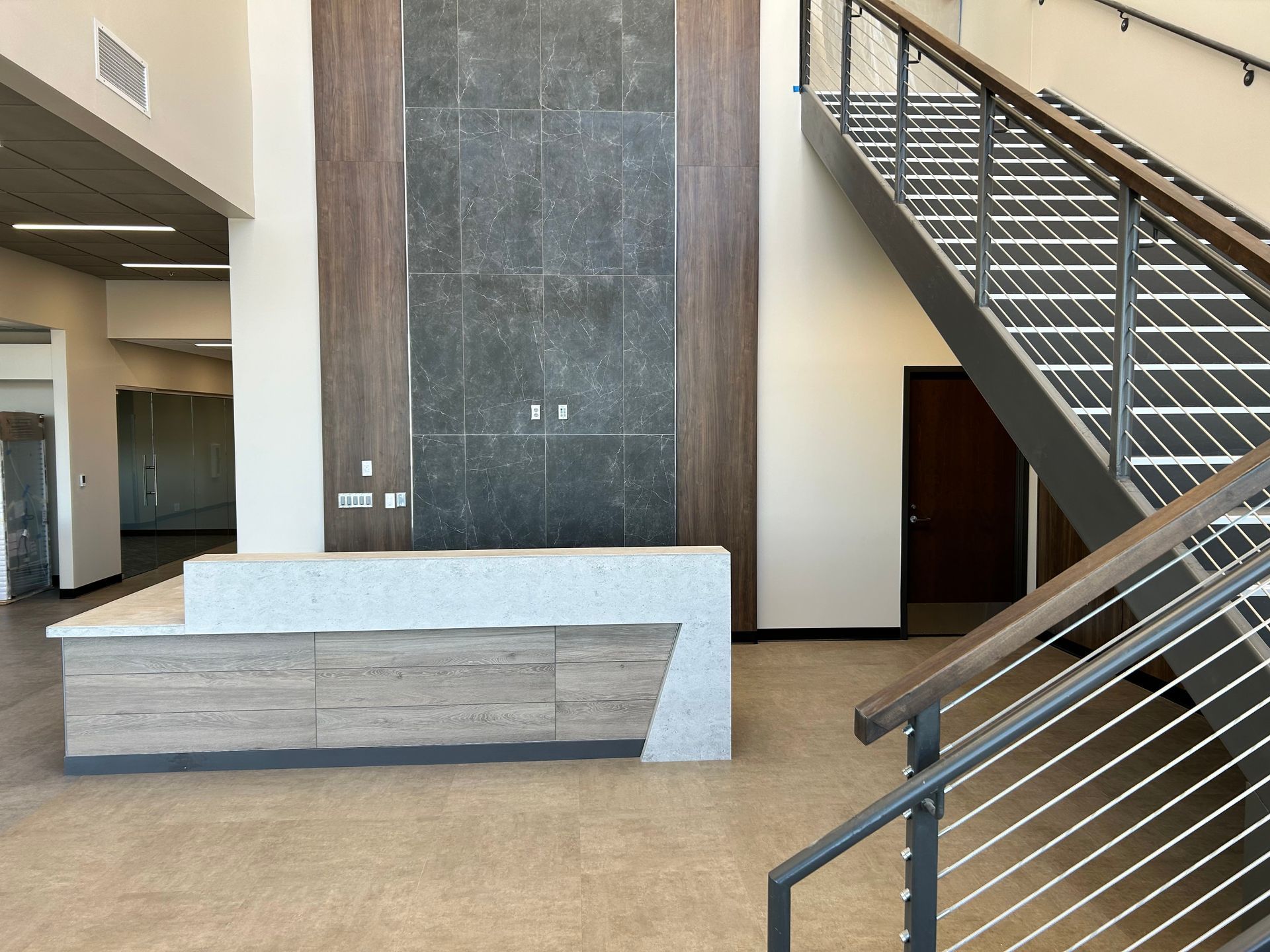 a lobby with a reception desk and stairs in a building . | Sioux City, IA | L&L Builders Co