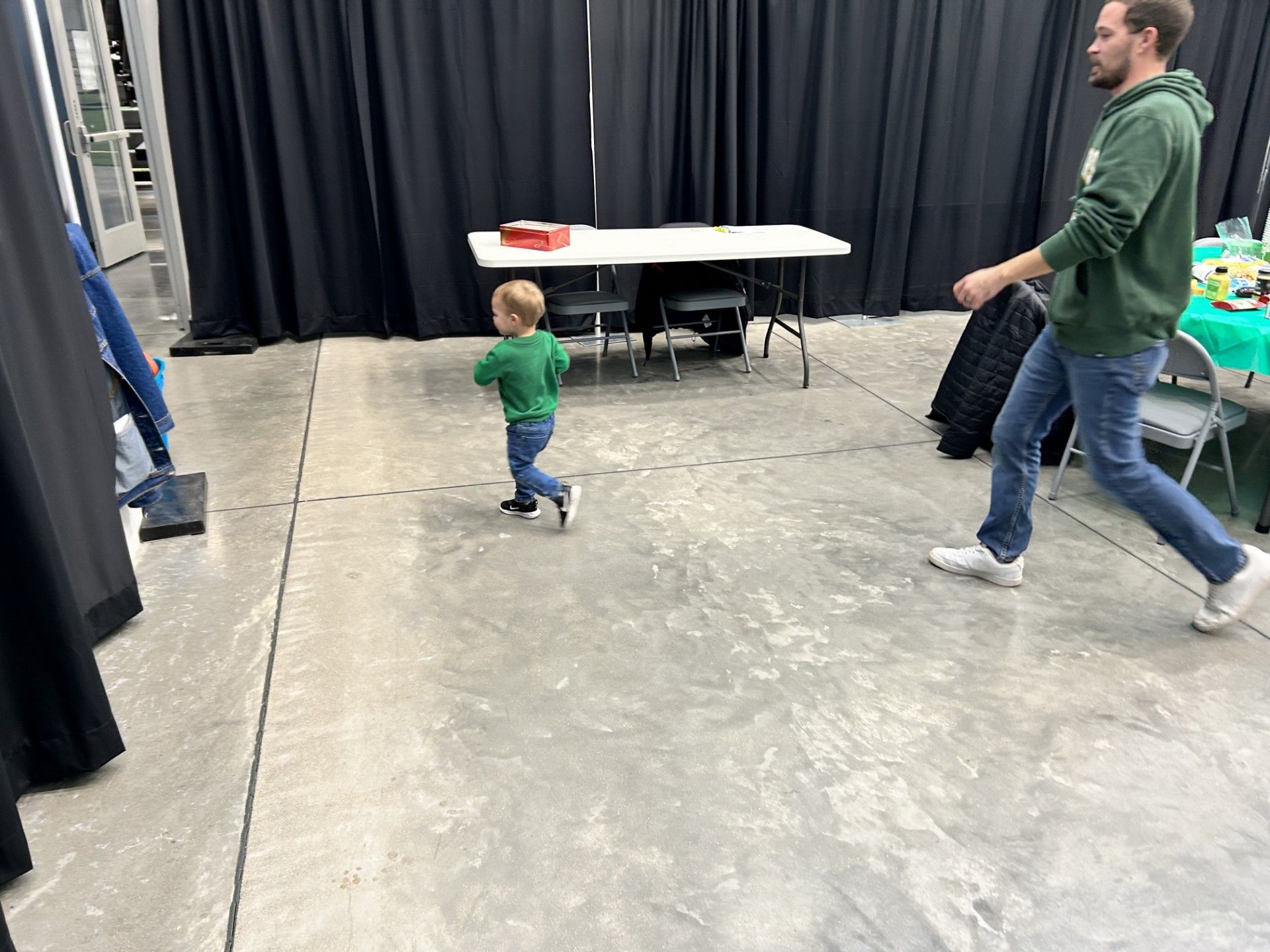 a man and a little boy are walking in a room .