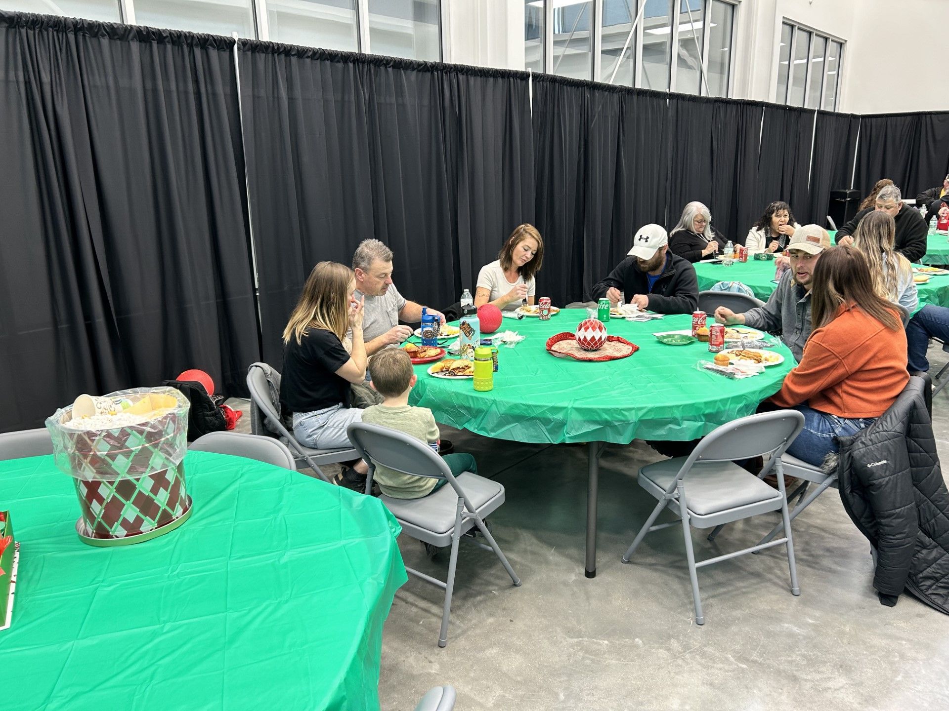 a group of people are sitting at tables with green tables cloths .