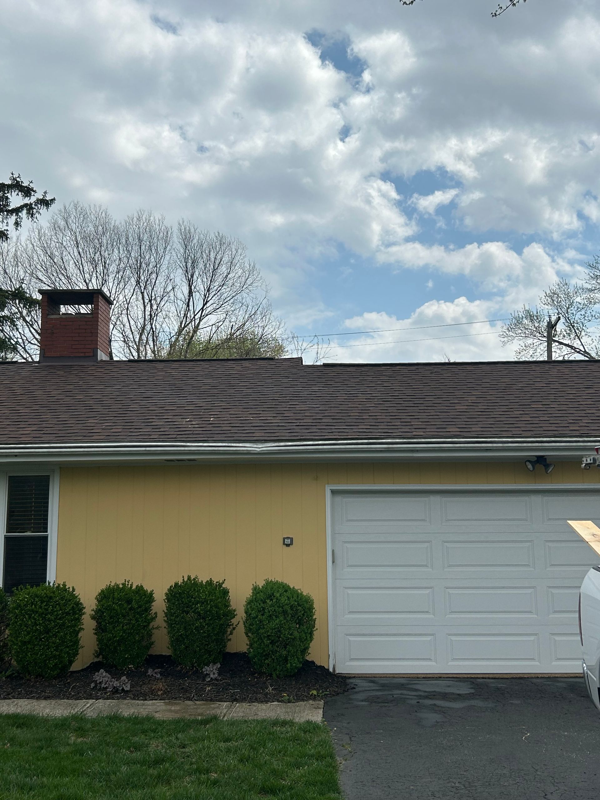 A view of a shingled roof valley where two roof slopes meet, featuring a metal flashing strip at the bottom.