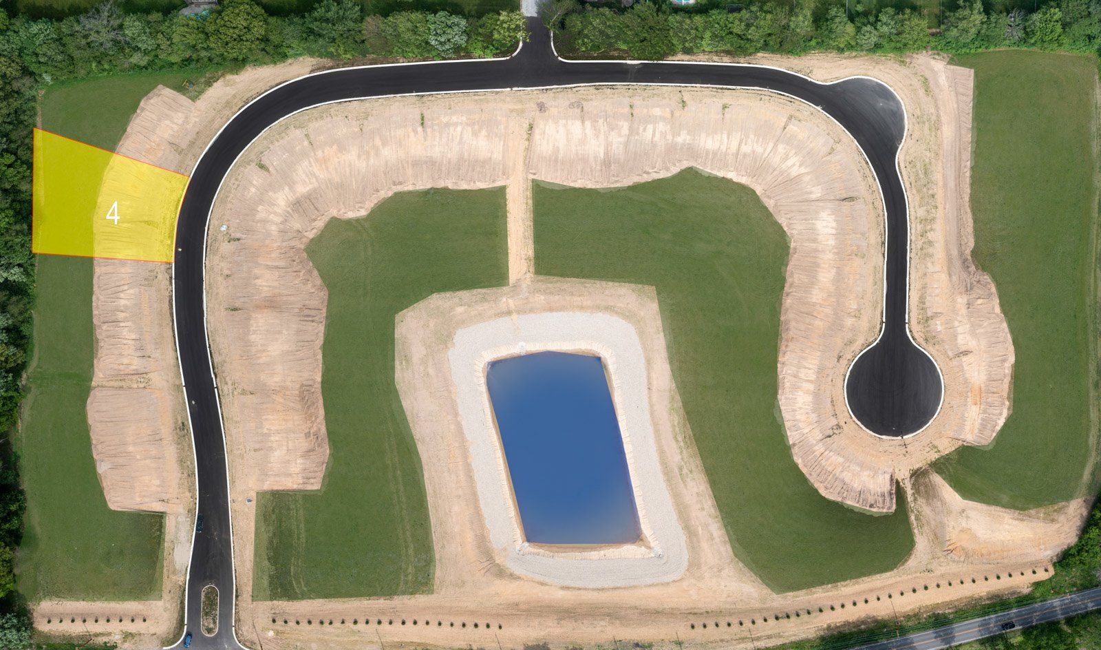 Aerial view of a new road in a construction zone. A yellow area indicates the start of the road.