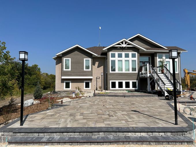 A two-story house with a wooden deck and patio, featuring a beige stucco exterior and a grass yard.