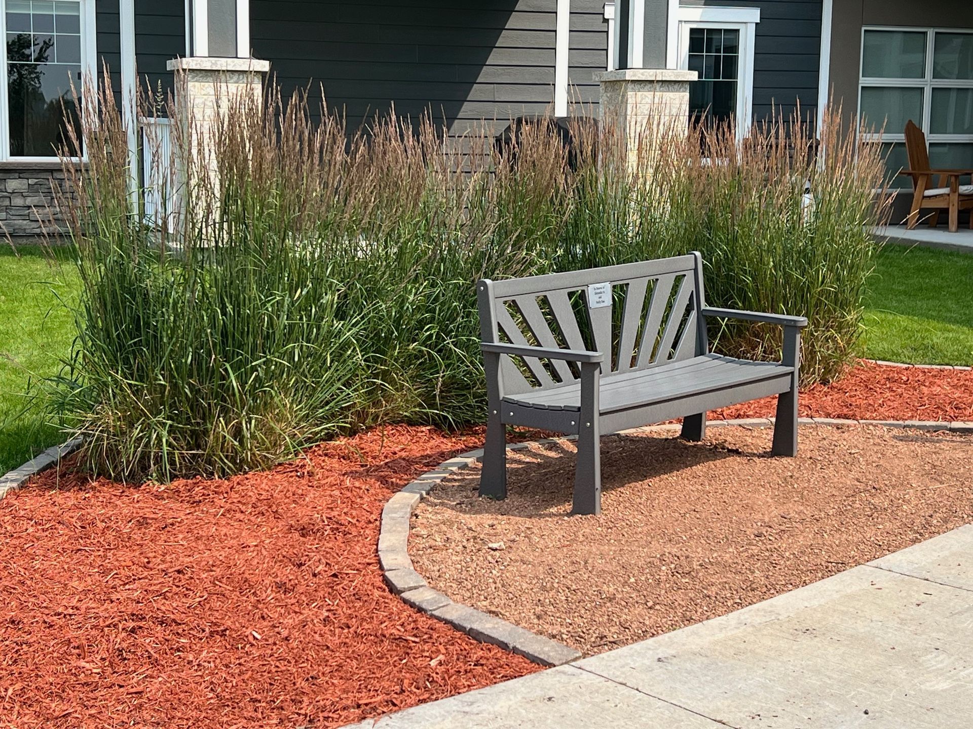 A person in work gloves uses a mallet to secure a tan stone into a mortar-set wall outdoors.