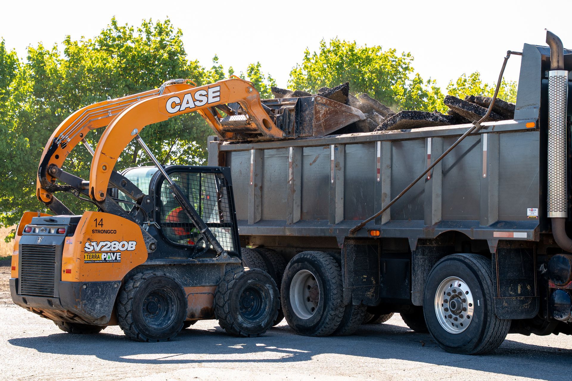 A case excavator is loading dirt into a dump truck.