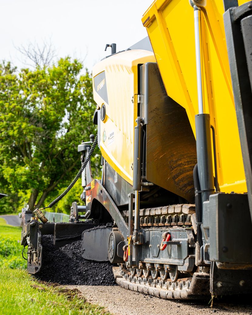 A yellow truck is driving down a dirt road.