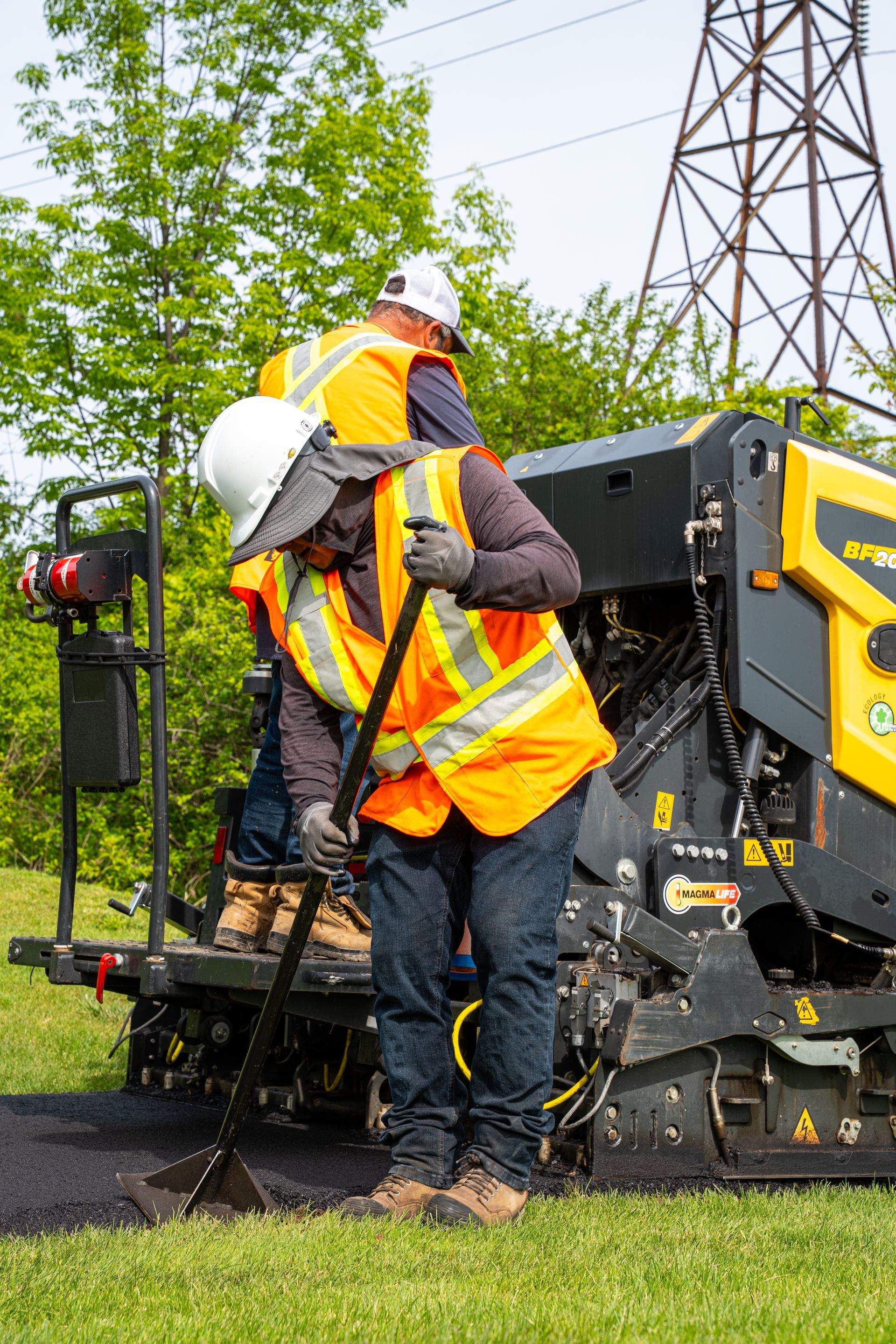 Two construction workers are working on a road.