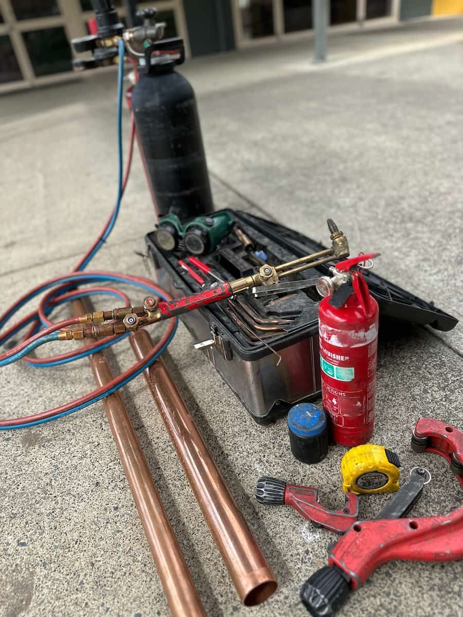 A Bunch Of Tools And Pipes Are Sitting On The Ground — Plumbmasters In Robina, QLD
