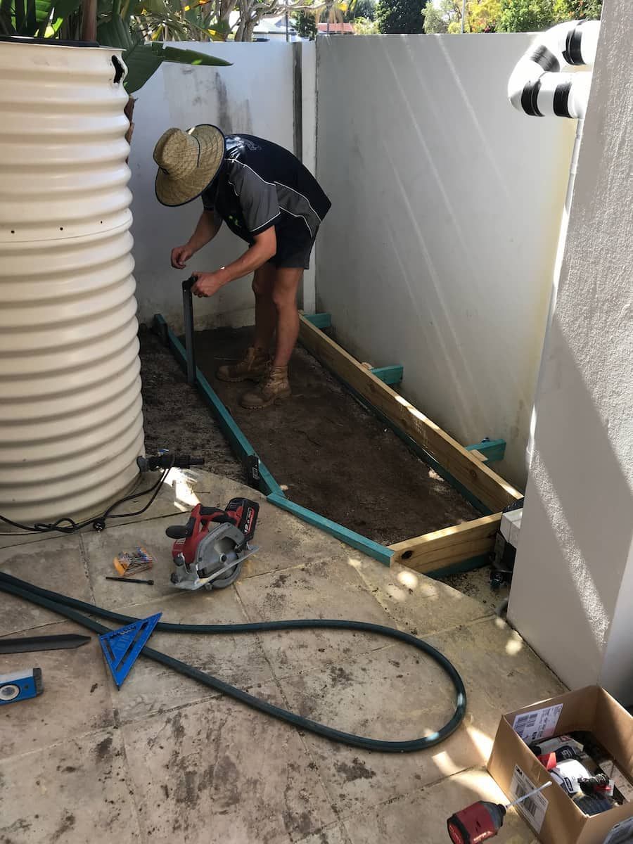 A Man Wearing A Straw Hat Is Working On A Garden — Plumbmasters In Burleigh Heads, QLD