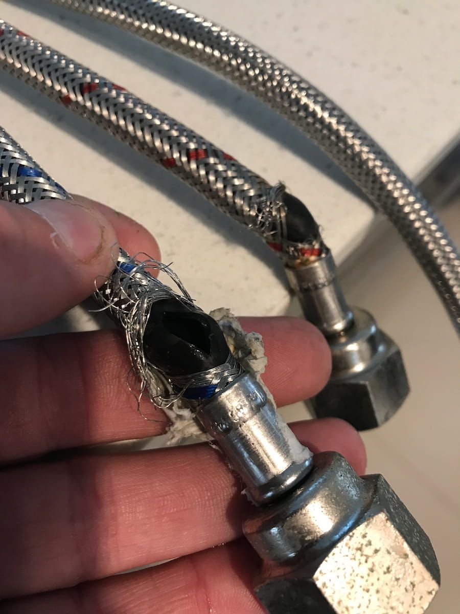 A Person Is Holding A Hose With A Hole In It — Plumbmasters In Robina, QLD