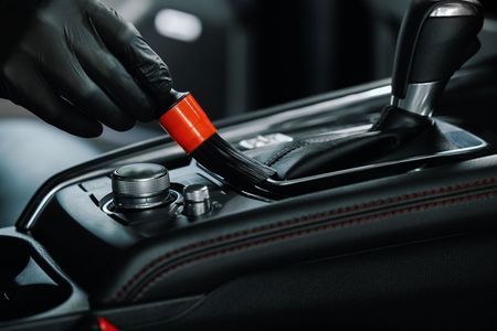 A person is cleaning the interior of a car with a vacuum cleaner.