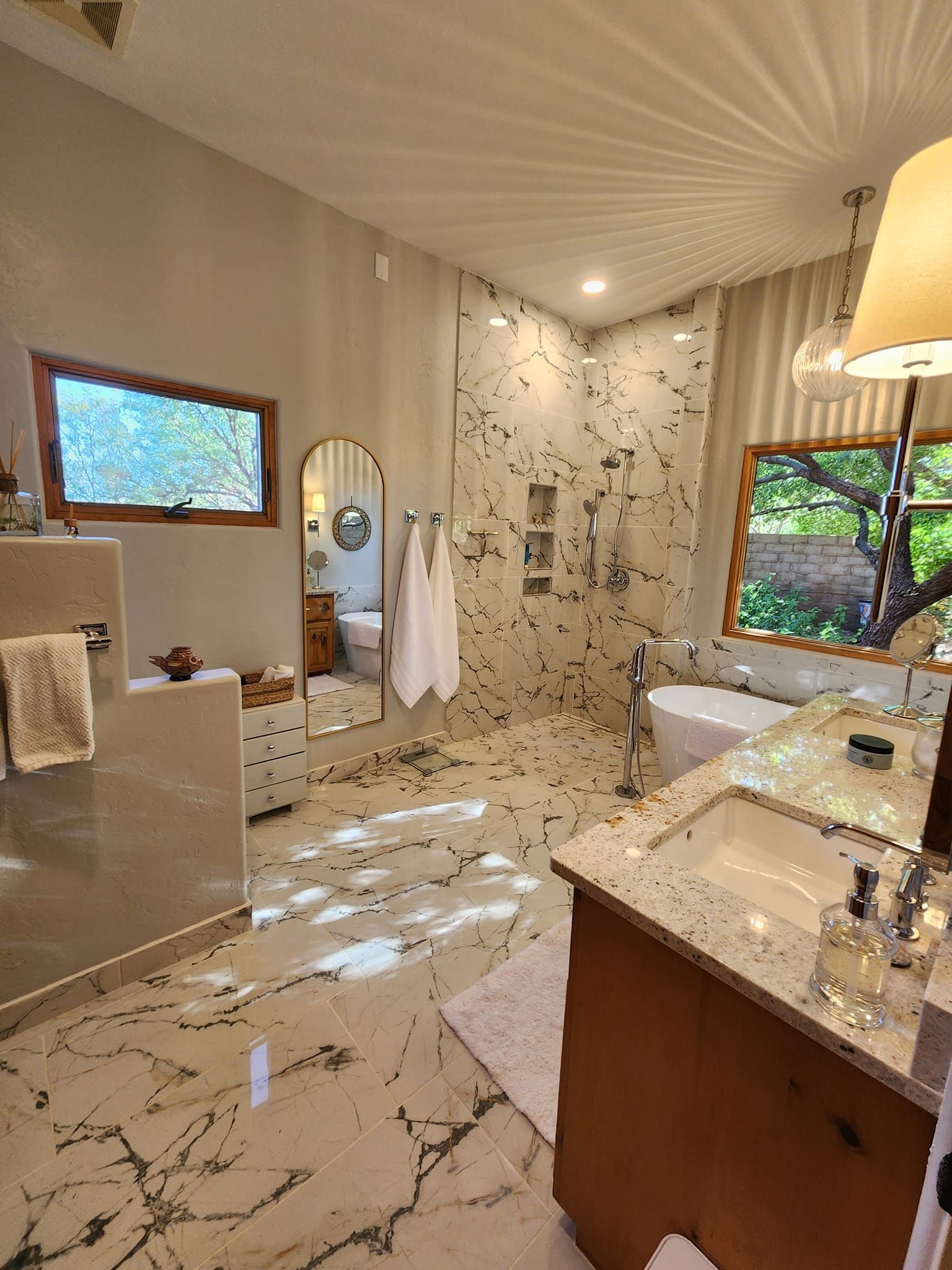 Luxurious bathroom with marble floors, glass shower, and freestanding tub.
