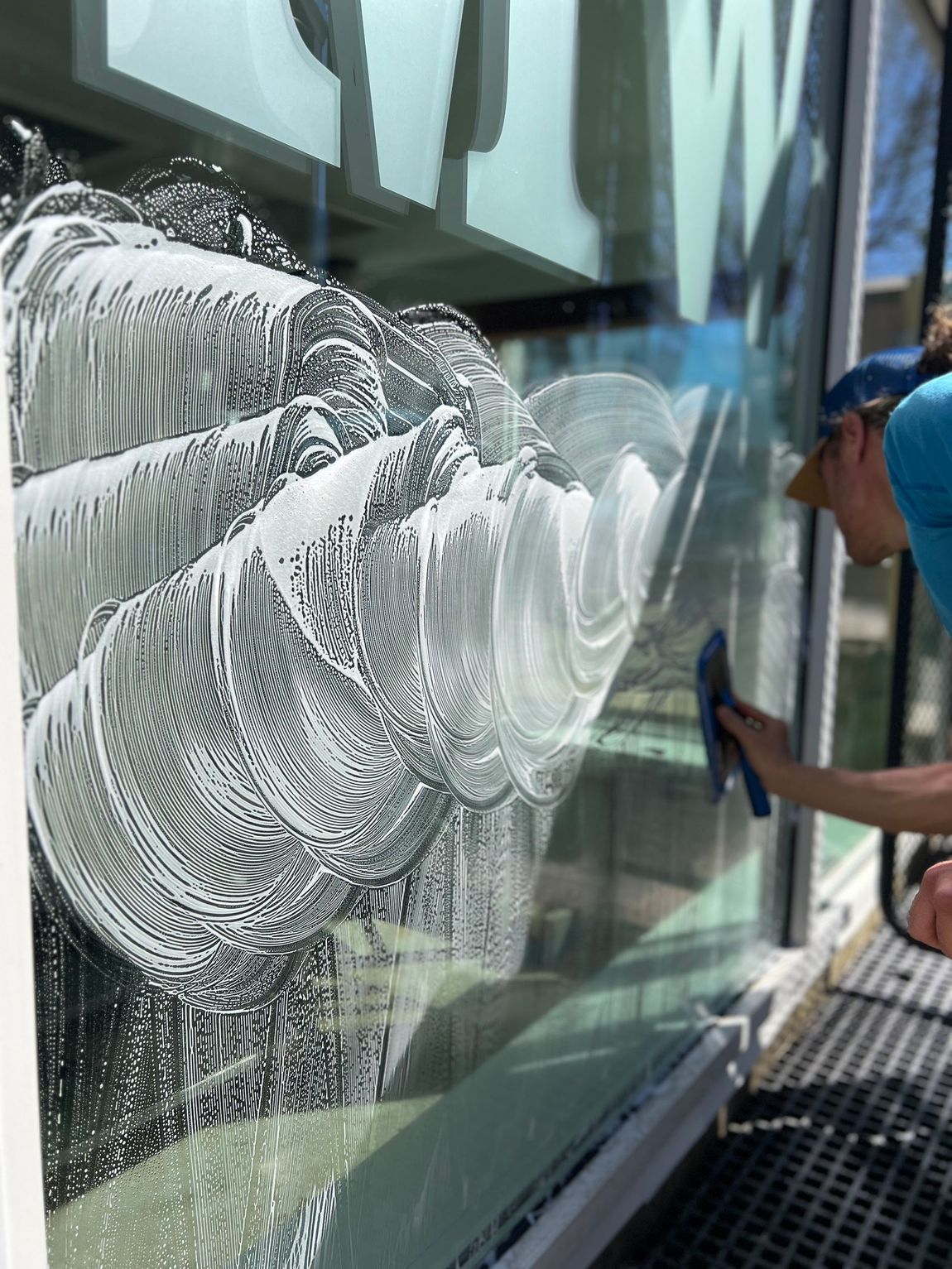 A dark-colored pickup truck towing a black flatbed trailer parked in an empty outdoor lot on an overcast day.