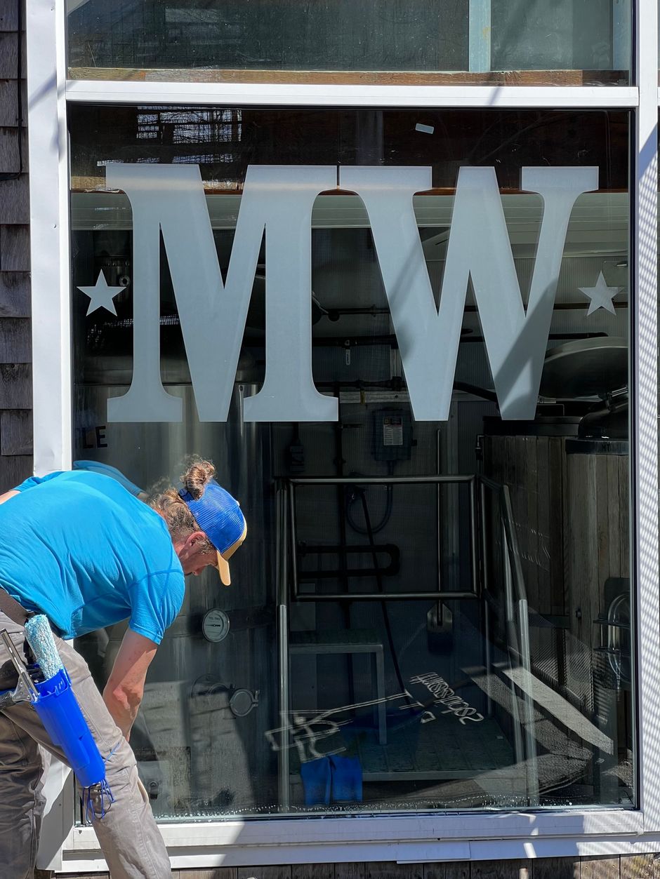 An interior view of a room under construction, featuring exposed ceiling rafters with insulation and a concrete floor.