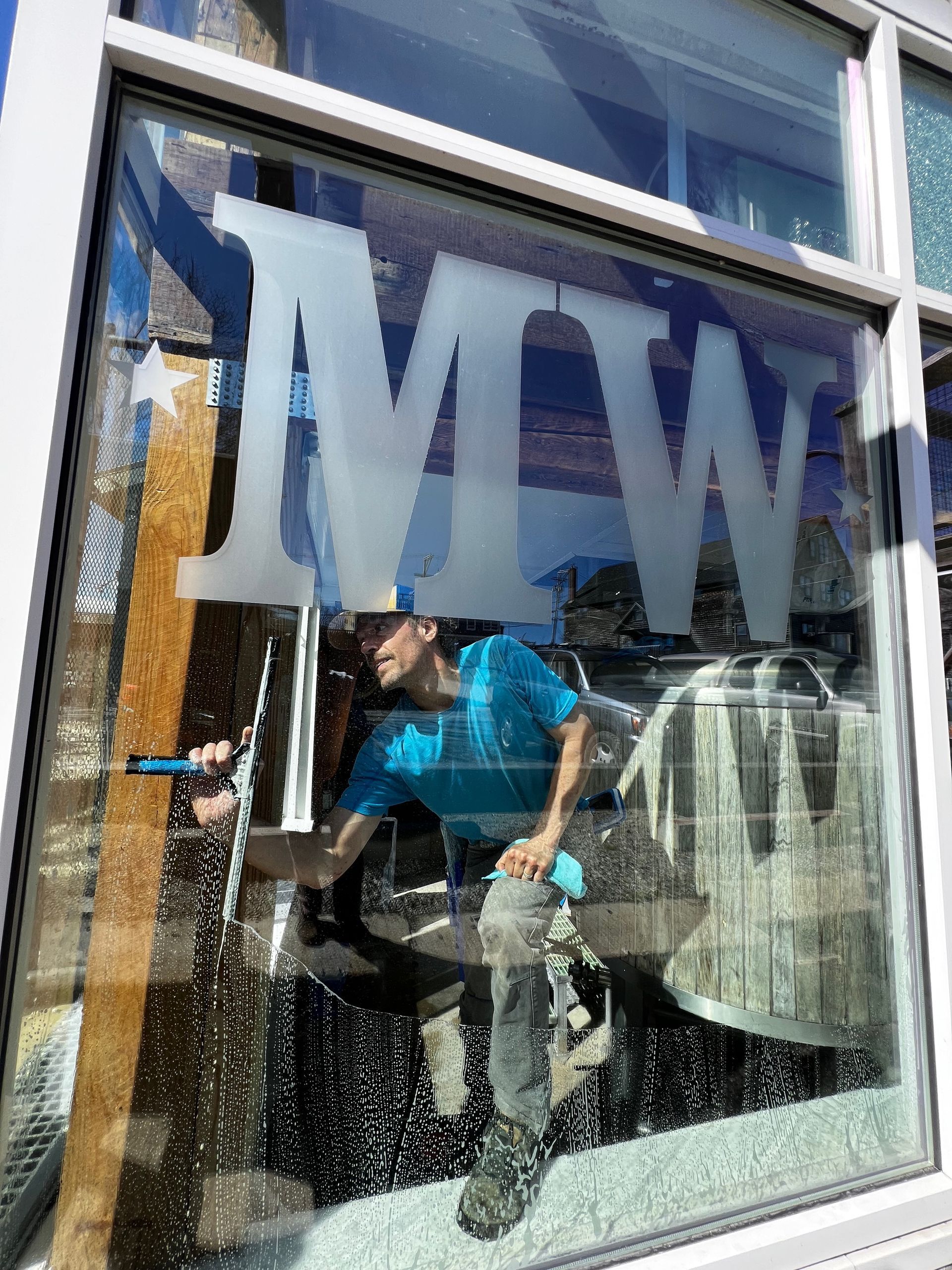 A basement laundry area with a washing machine, utility sink, and clothes dryer on a concrete floor beneath exposed beams.