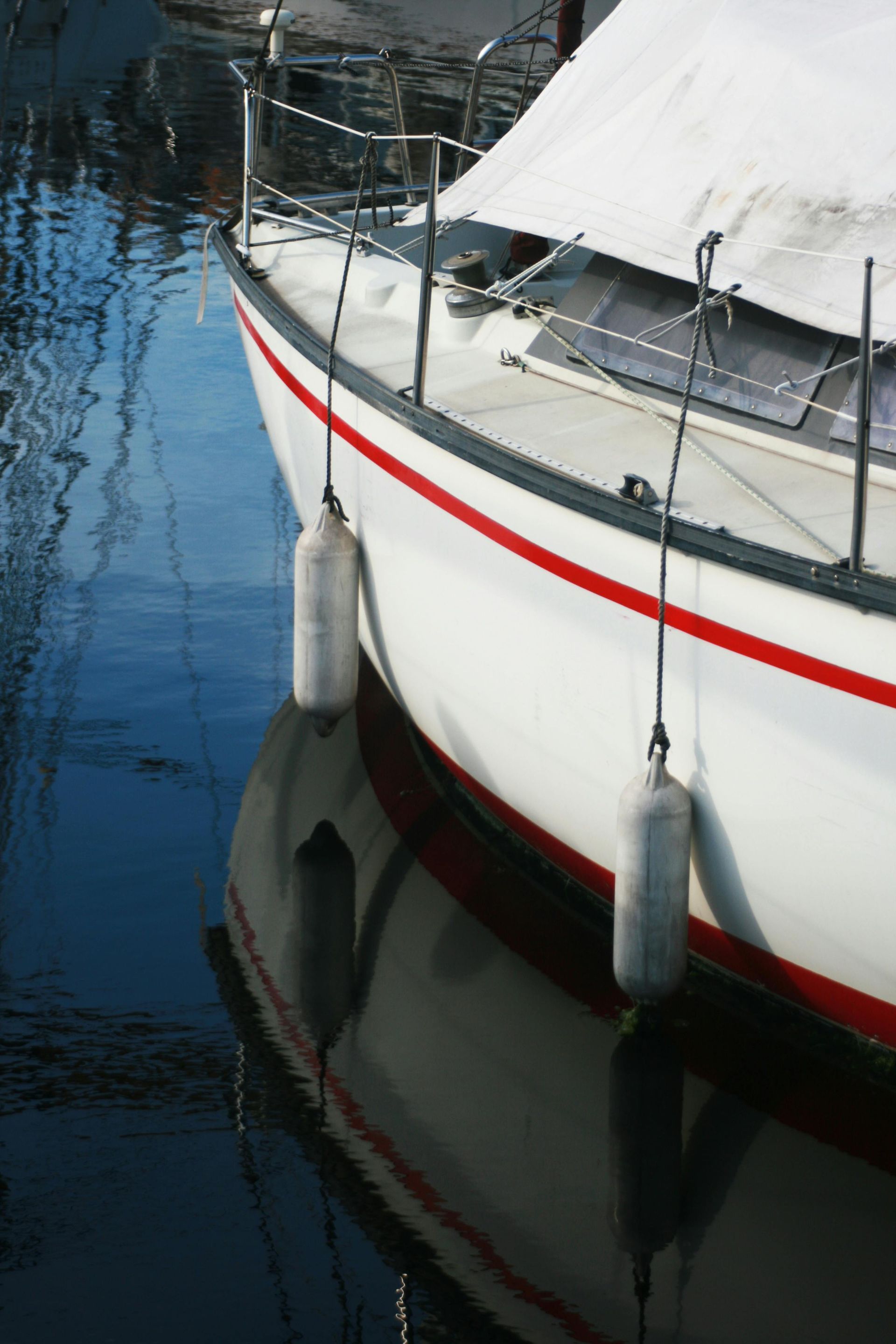 A yellow CAT excavator parked next to several green dumpsters filled with debris near a building with an American flag.