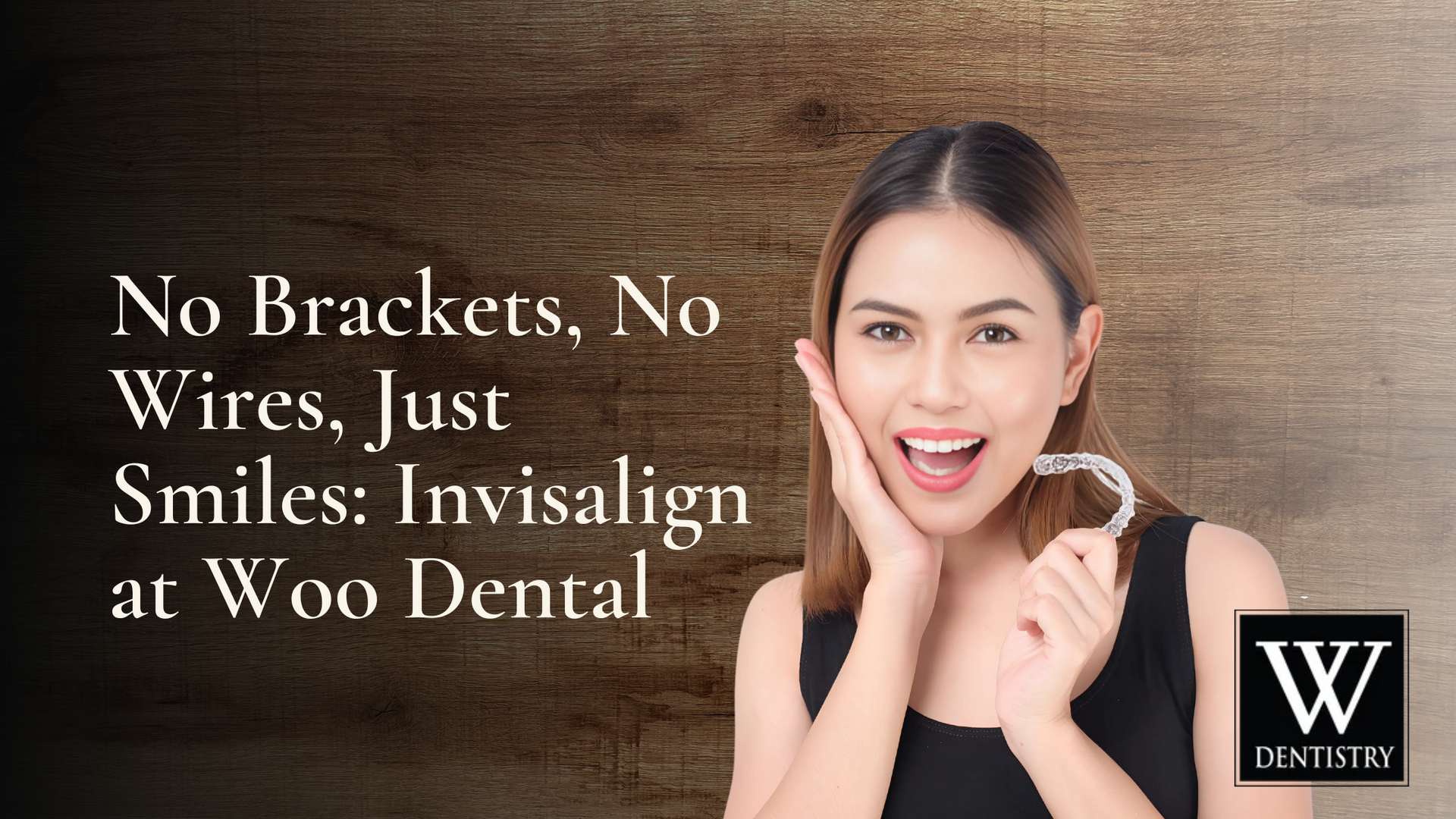 A woman is smiling while holding a clear retainer in her hand.