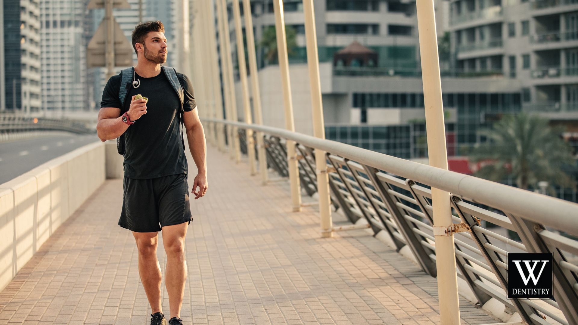 A man with a backpack is walking across a bridge.