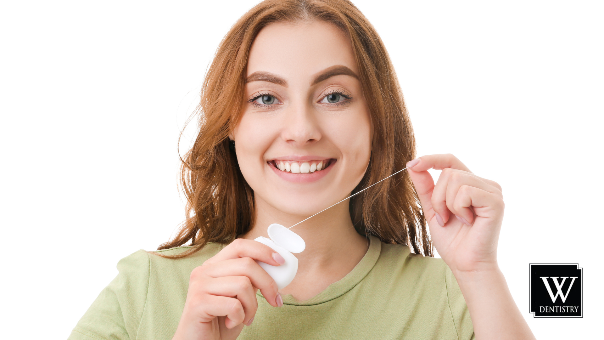 A woman is smiling while flossing her teeth.