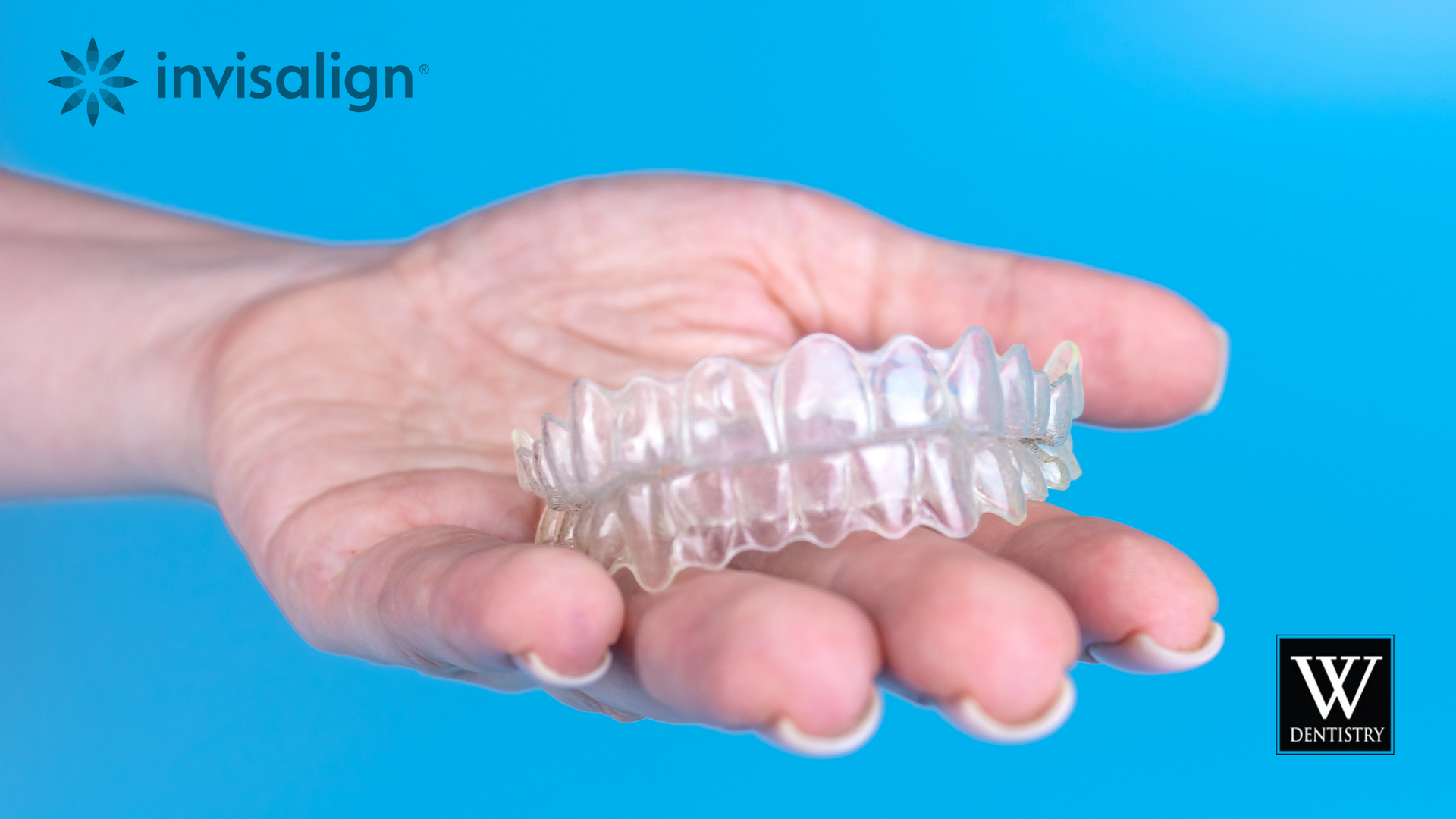 A person is holding a clear retainer in their hand.