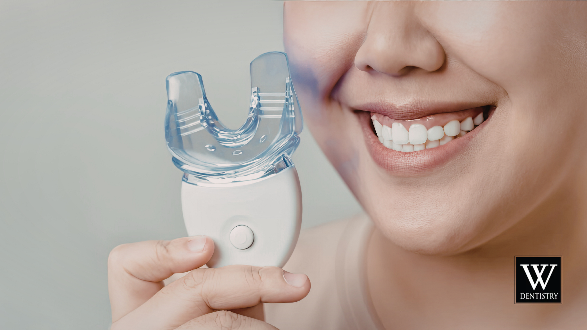 Person smiling while holding a clear blue mouthguard device near their face