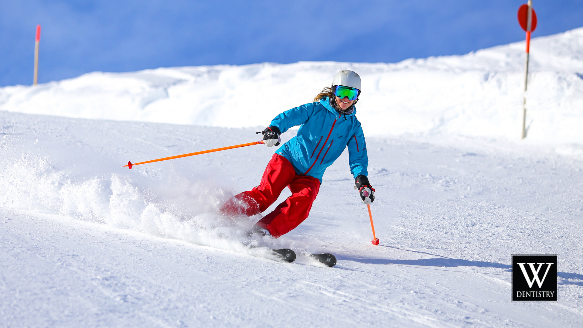 A woman is skiing down a snow covered slope.