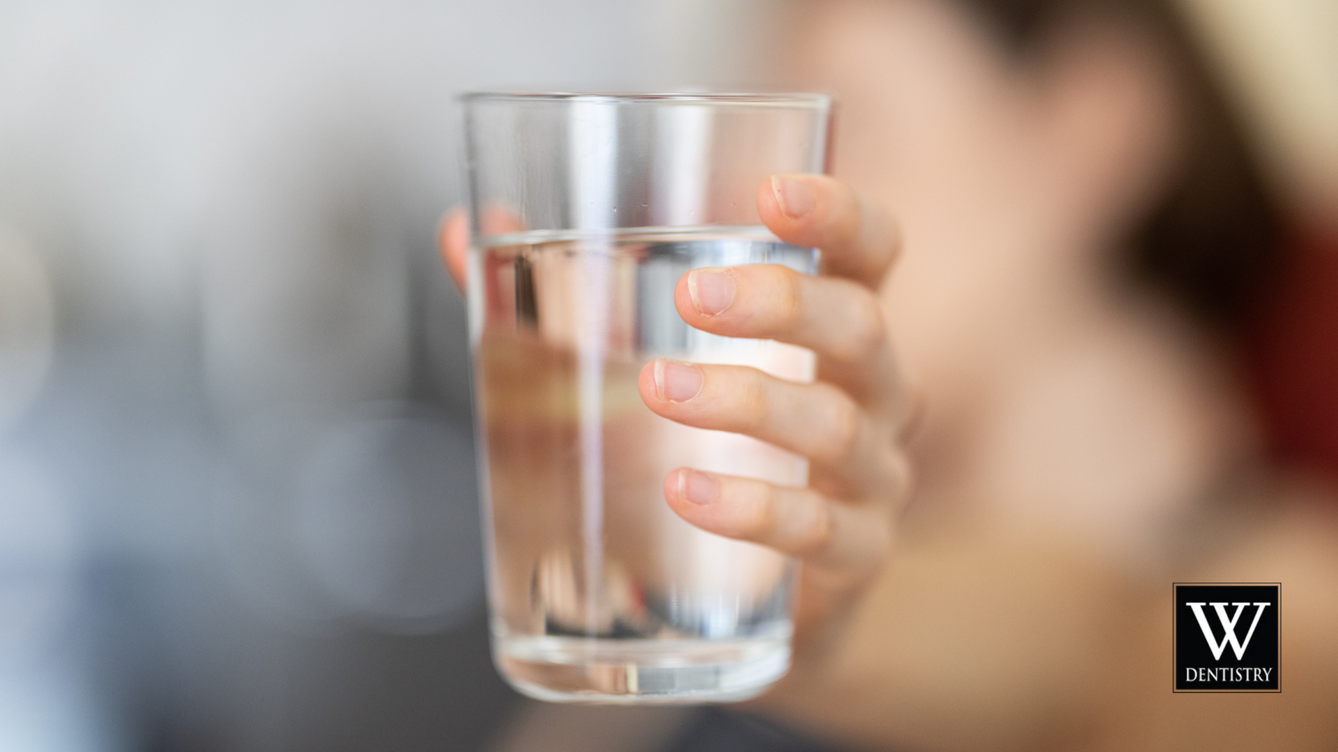 A woman is holding a glass of water in her hand.