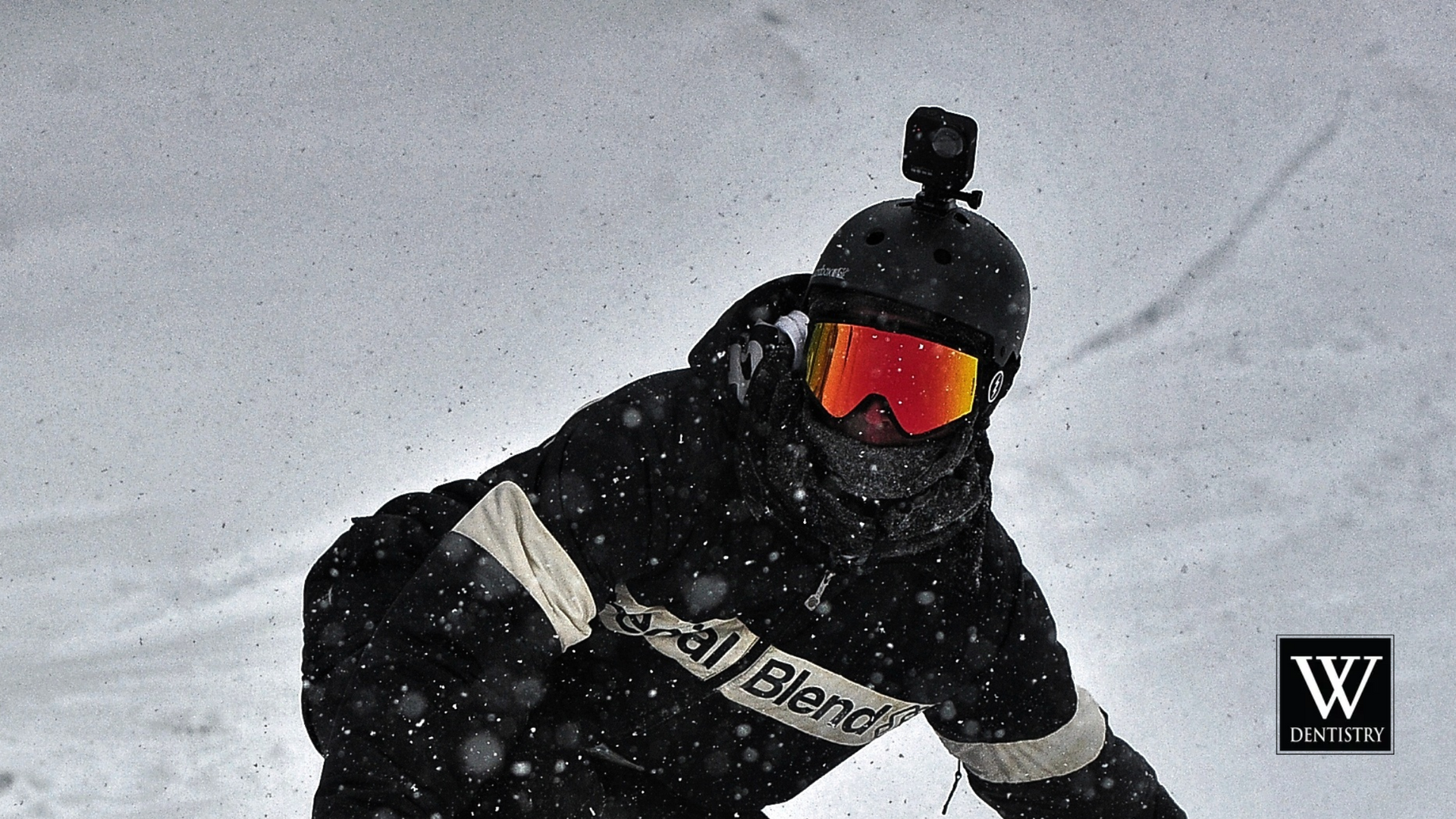 A snowboarder wearing a helmet and goggles is riding down a snowy slope.