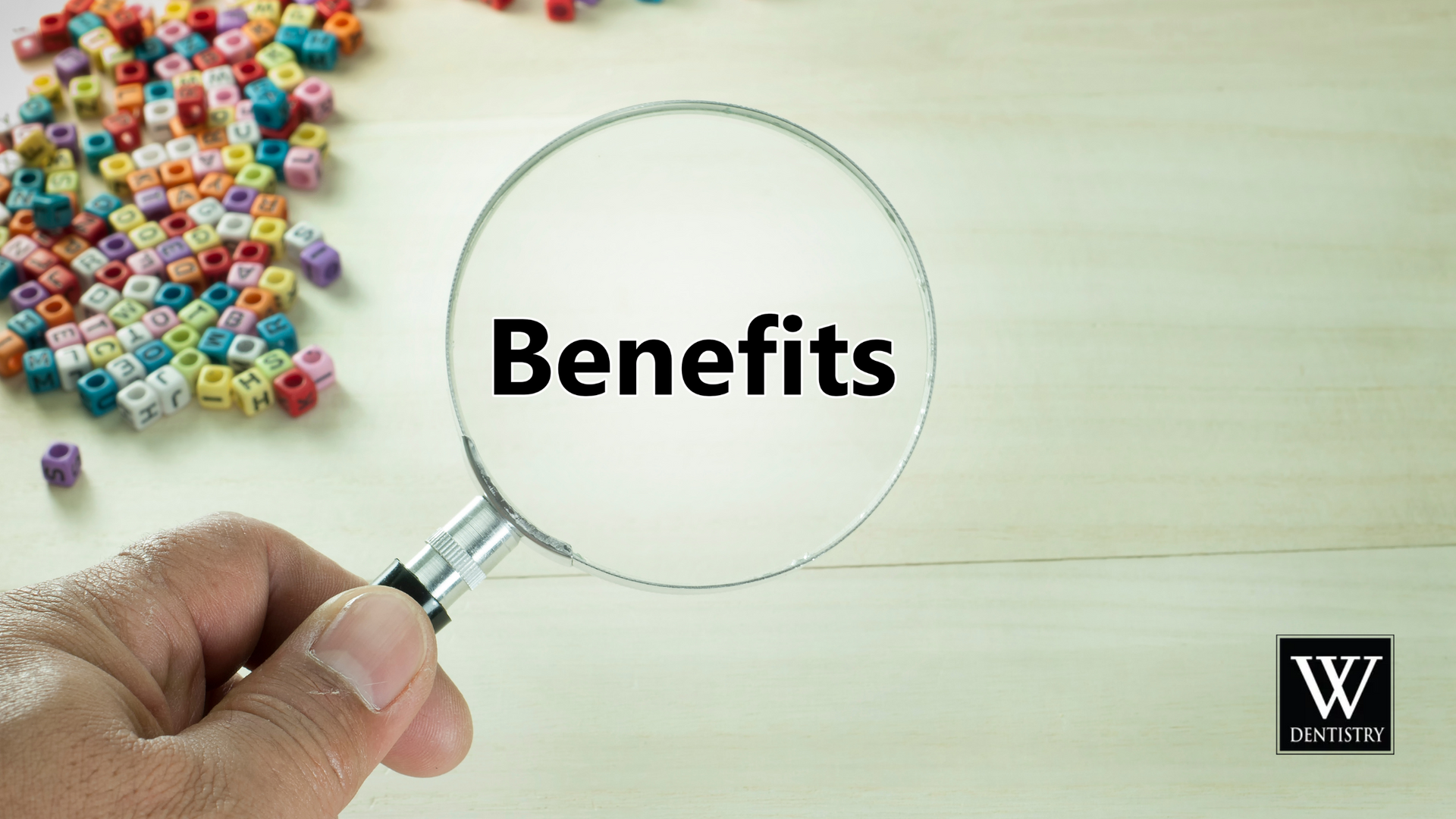 A person is holding a magnifying glass with the word benefits written on it.