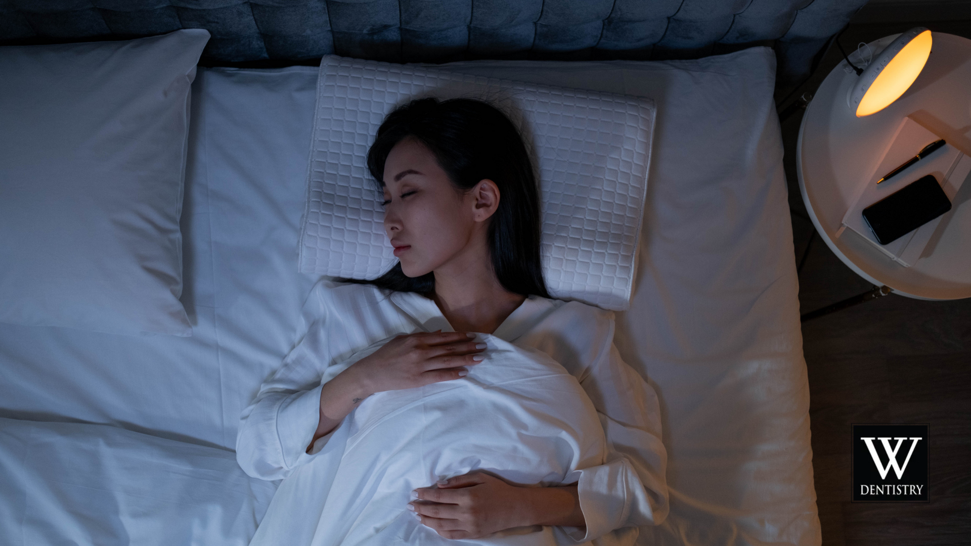 A woman is sleeping on a bed with white sheets and pillows.