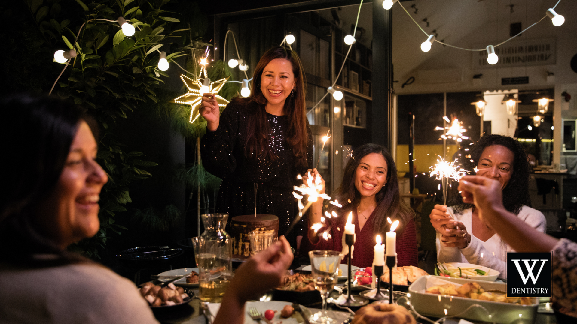 A group of women are sitting at a table holding sparklers.