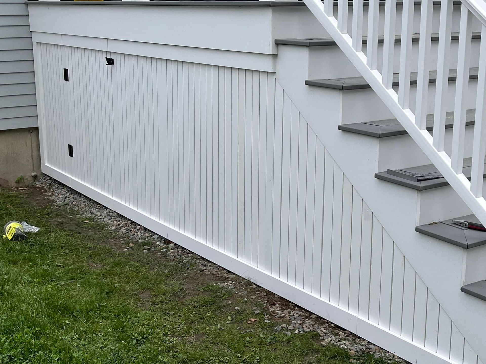 A white fence surrounds a set of stairs leading up to a deck.