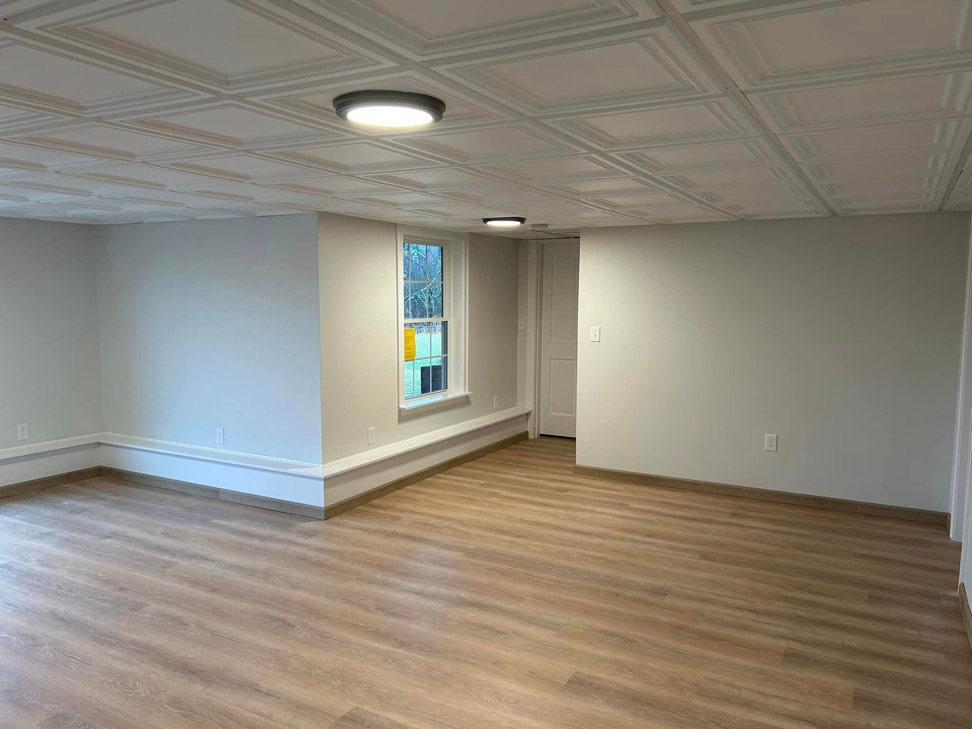 A large empty room with hardwood floors and white walls.