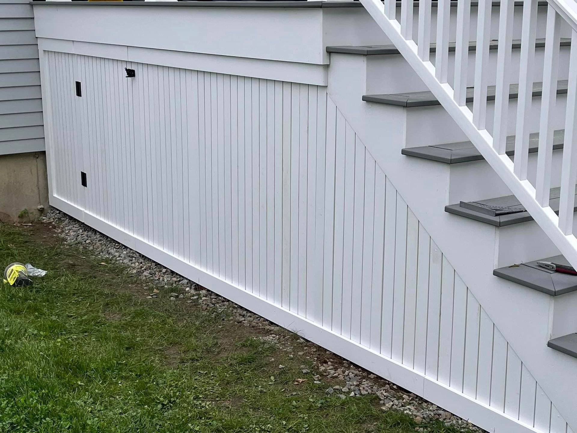 A white fence surrounds a set of stairs leading up to a deck.
